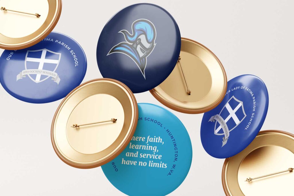 The Our Lady of Fatima mascot, heraldic shield, and mission statement were rendered on pins to demonstrate how the school might use their new marks on swag.