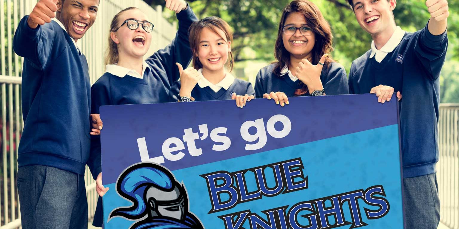 Five middle school students give thumbs-up while posing outdoors with a sign that reads, "Let's Go Blue Knights."